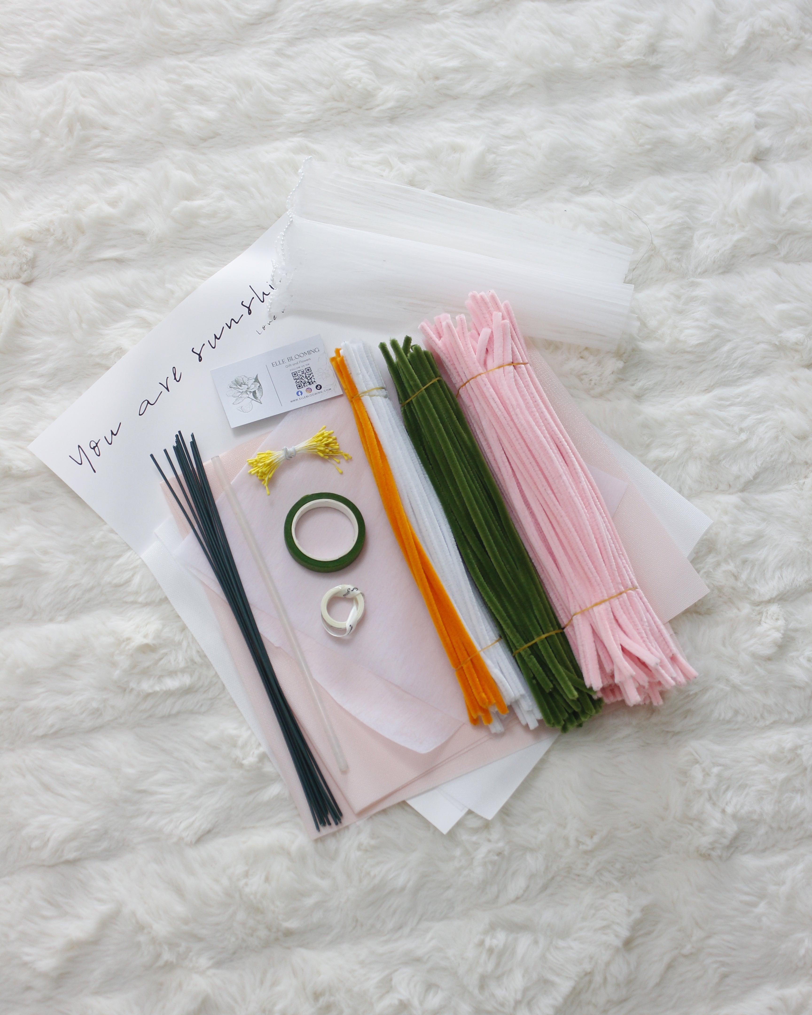 Assorted stationery items including ribbons and a ring on a textured white surface
